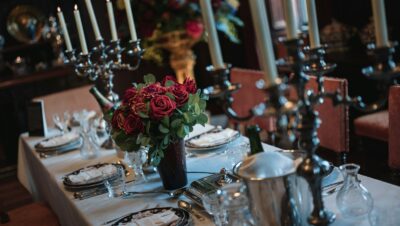 Mesa preparada con rosas rojas y candelabros para celebrar las bodas de granate